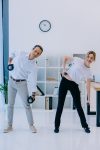 mature businessman with his female personal trainer working out with dumbbells at office