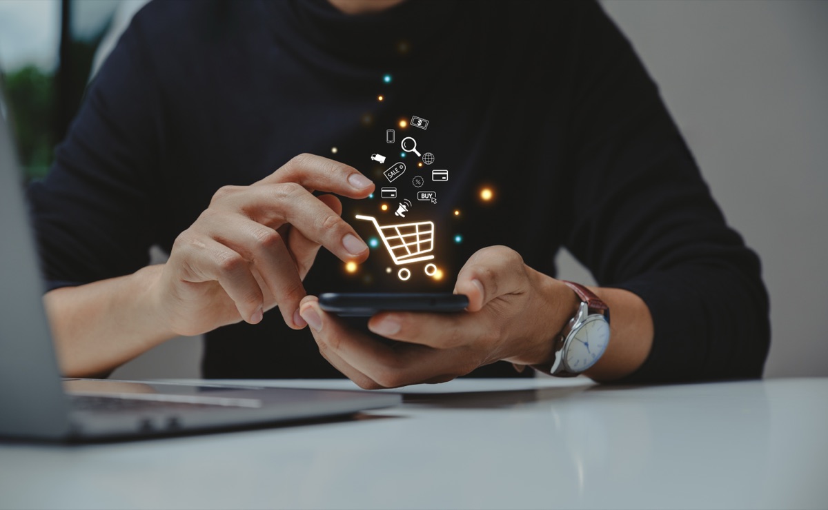 Dłonie trzymające smartfon z ikoną koszyka zakupowego – sprzedaż na marketplace